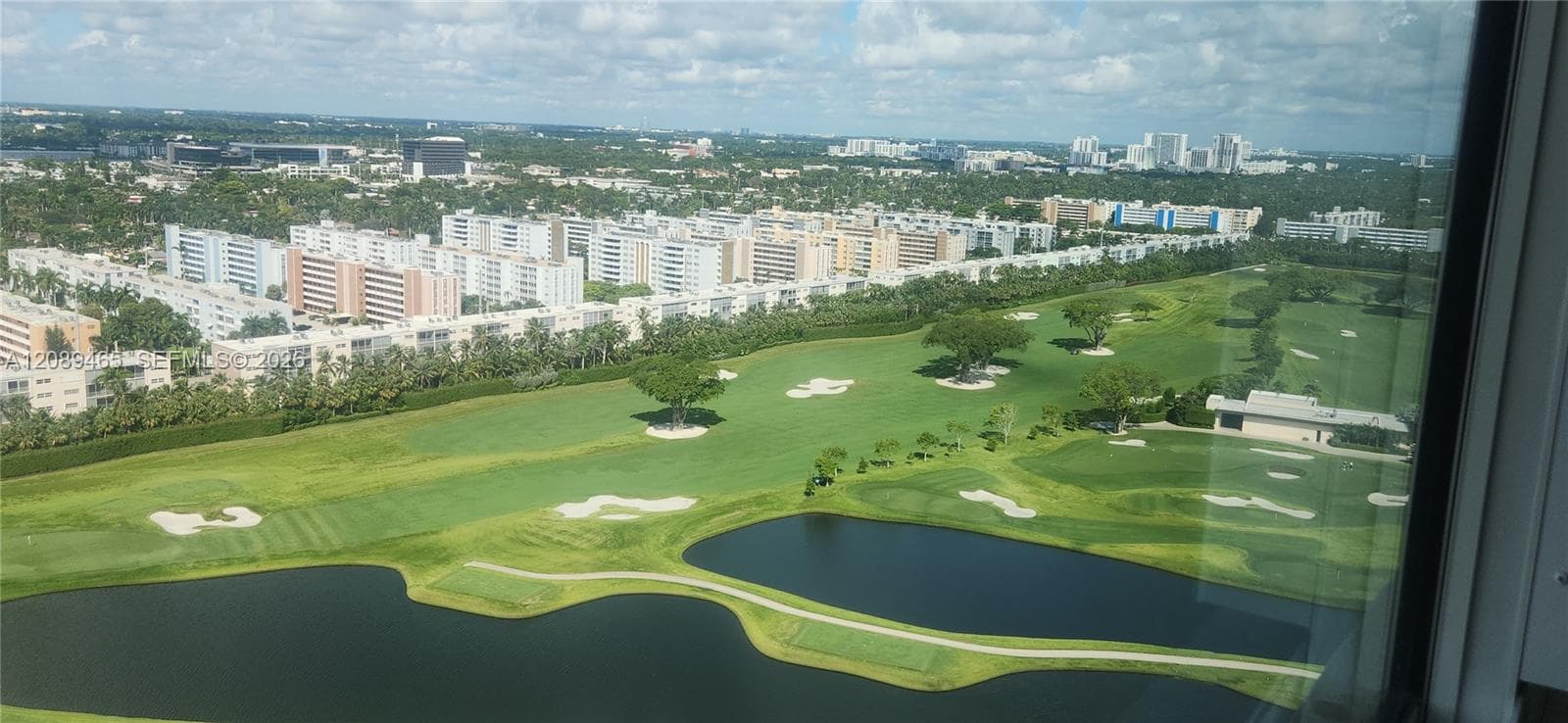 High-altitude perspective featuring expansive golf course fairways, multiple water hazards, and mature landscaping