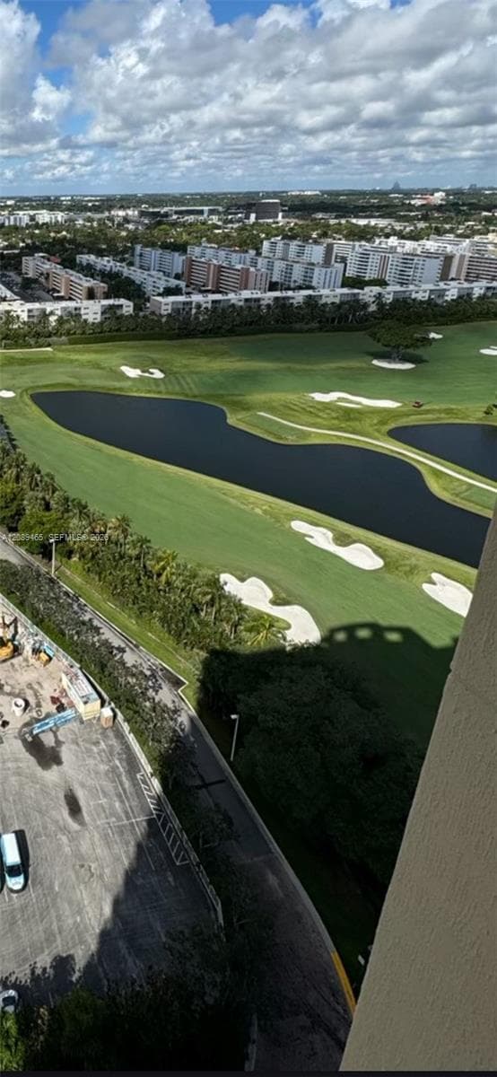 Aerial perspective featuring a golf course expanse, water hazards, sand bunkers, and mature perimeter trees