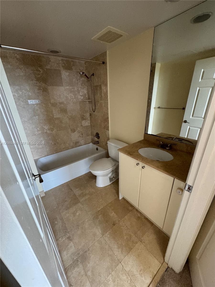 Guest Bathroom featuring natural stone tile flooring and tub surround, vanity with an integrated oval sink