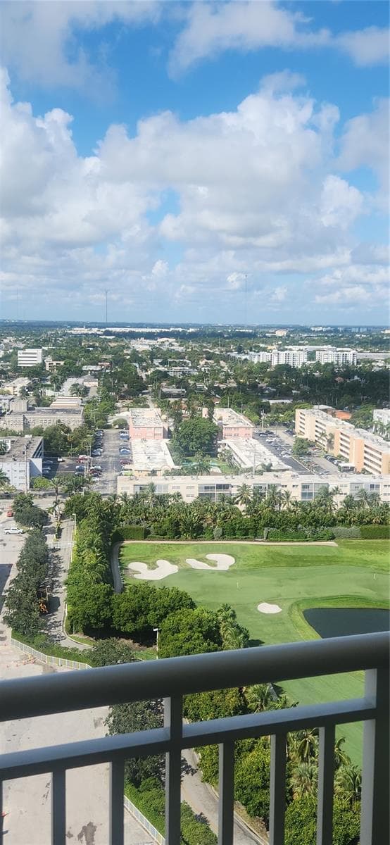 Elevated perspective of the surrounding area featuring a multi-level golf course, manicured grounds, mature trees, and urban landscape