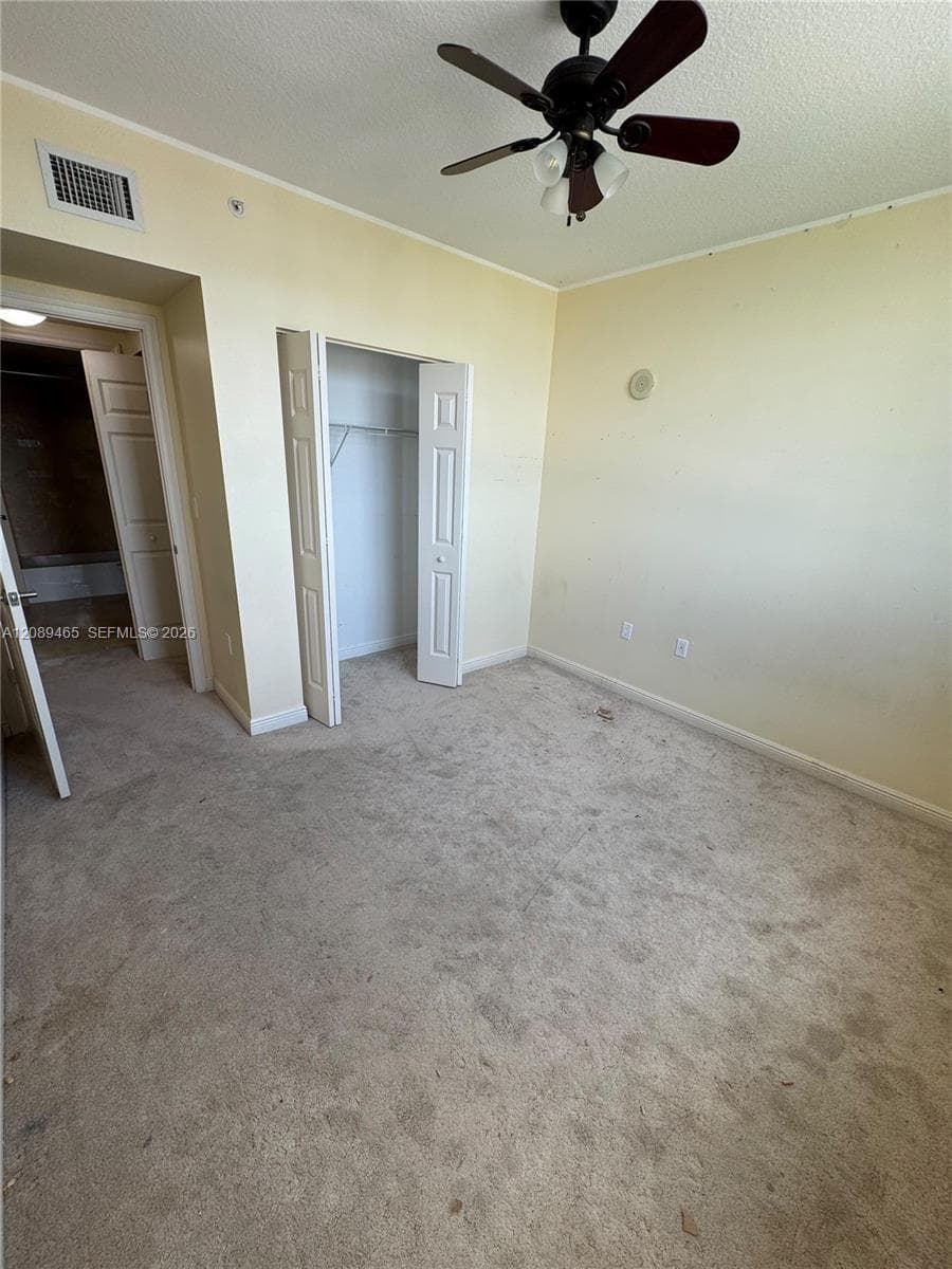 2nd bedroom (could be a den/office/baby room /zen room  etc...Neutral-toned room featuring carpeting, a ceiling fan with integrated lighting, and a bi-fold door closet