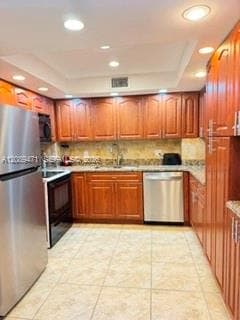 Kitchen featuring wood cabinetry, stainless steel appliances, stone-surface countertops, tile backsplash, and recessed lighting