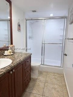 Bathroom featuring a wood-finish vanity with stone-patterned countertop, an integrated sink, tiled flooring, and a shower with sliding glass doors