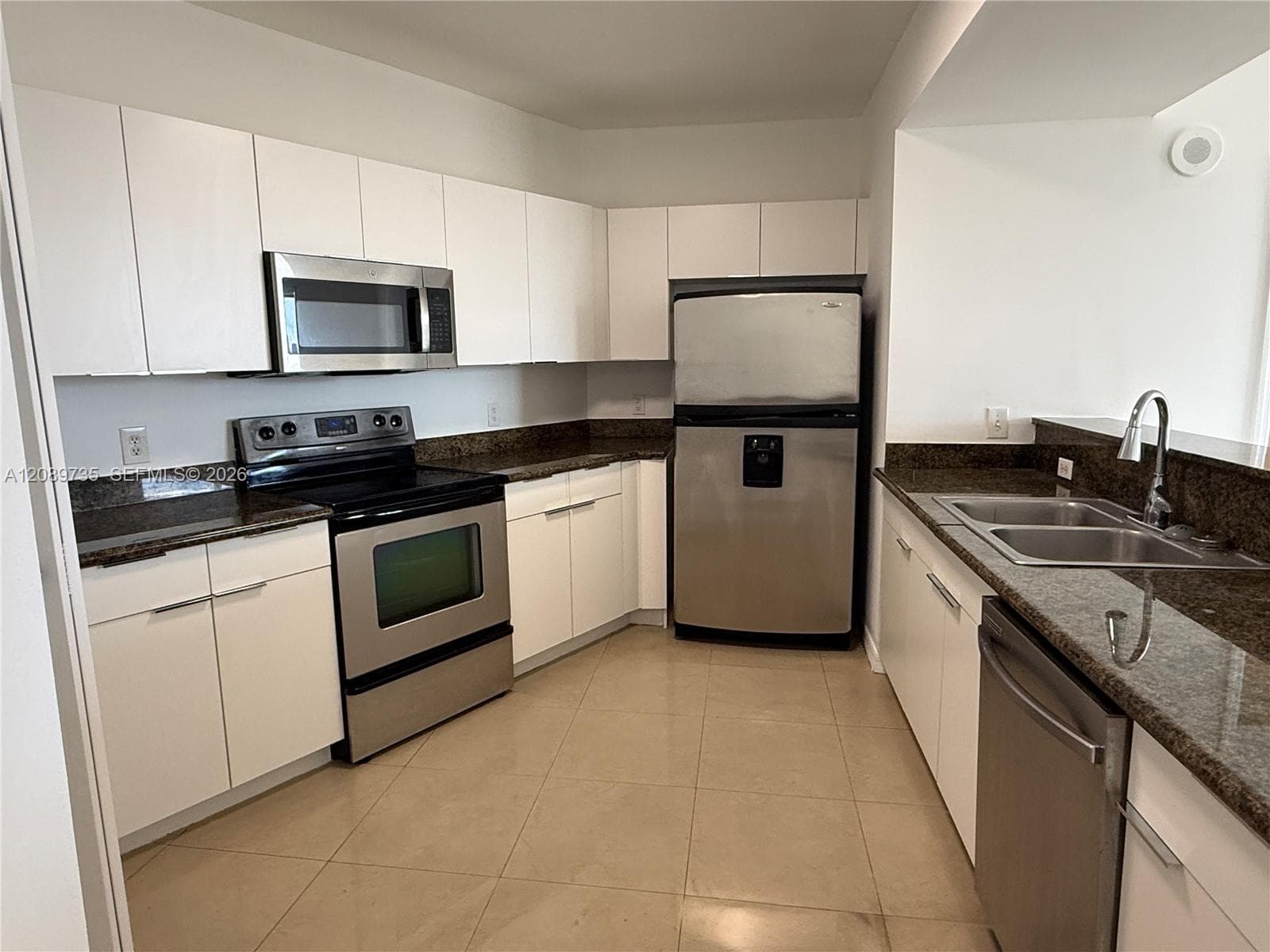 Kitchen featuring flat-panel white cabinetry, stone-finish countertops, stainless steel appliances, ceramic tile flooring, and a dual-basin sink with a pull-down faucet