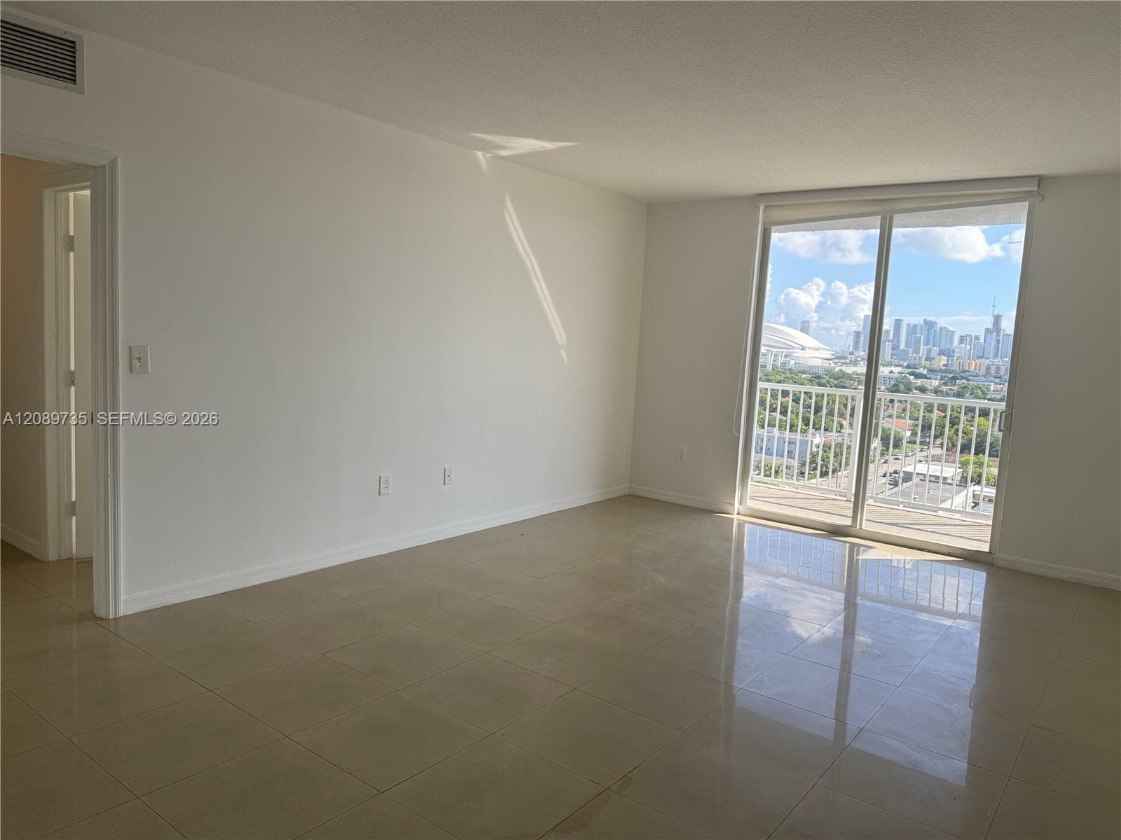 Living space featuring large-format tile flooring, expansive sliding glass doors, and a private balcony with urban skyline scenery