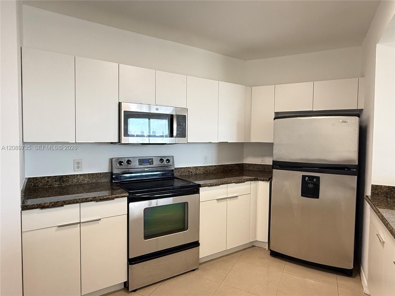 Kitchen featuring flat-panel white cabinetry, stone-finish countertops, tile flooring, and integrated stainless steel appliances