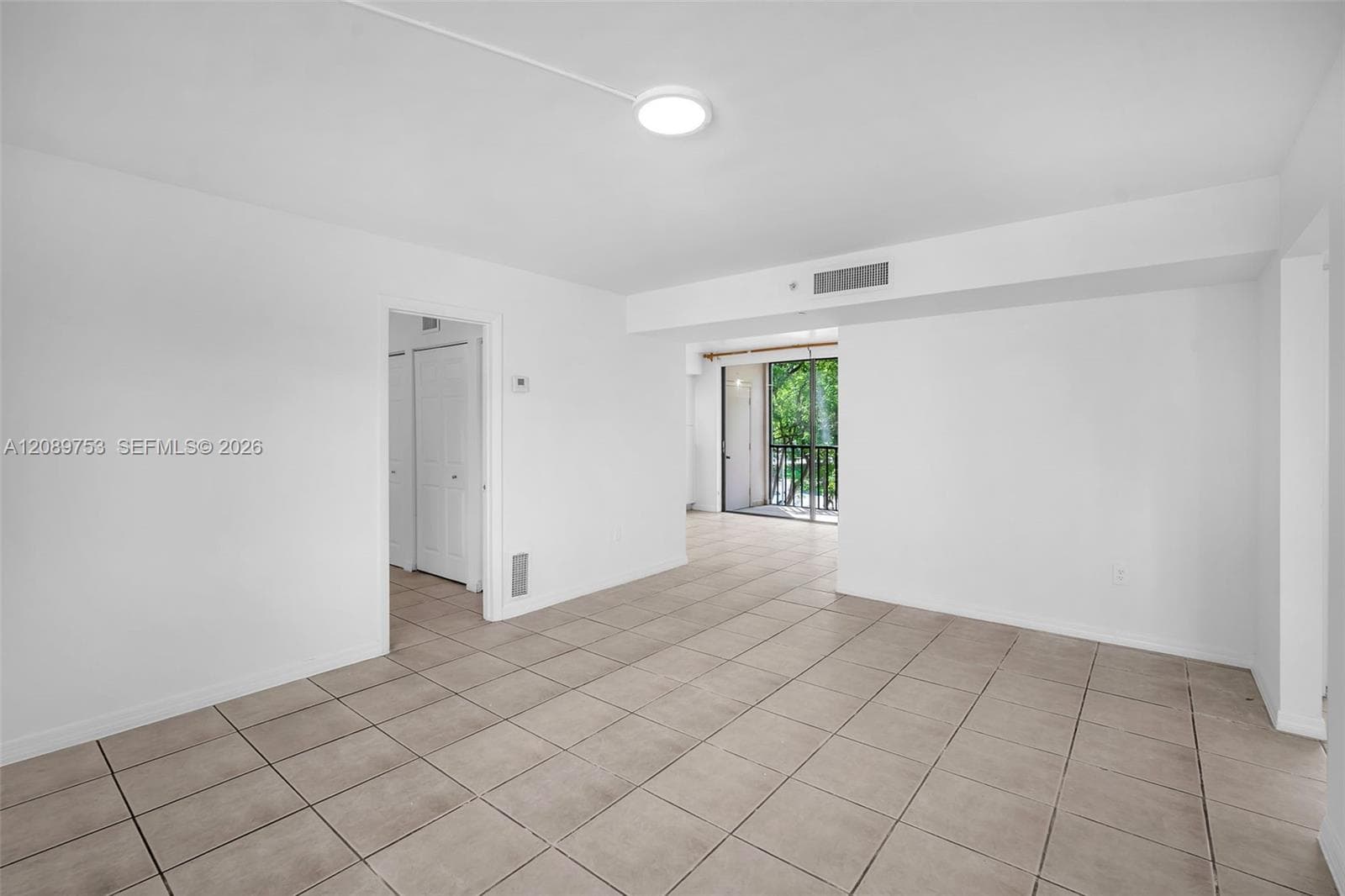 Neutral-toned ceramic tile flooring, clean white wall finishes, and a balcony with sliding glass doors