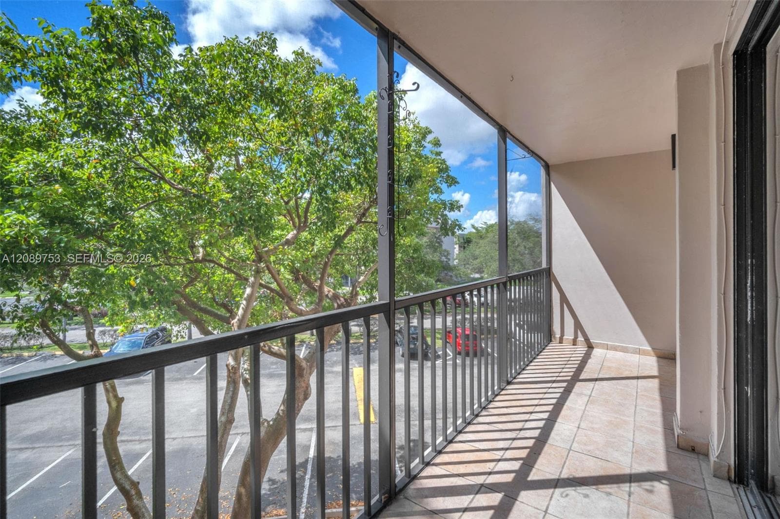 Covered balcony featuring tile flooring and a full-height metal screen enclosure