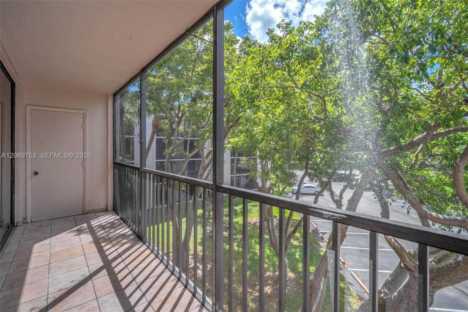 Covered balcony featuring tile flooring, metal railings, and screen enclosure