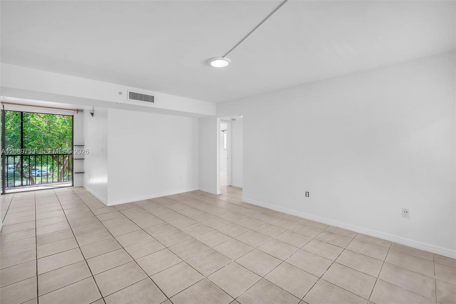 Neutral-toned ceramic tile flooring, expansive windowed wall, built-in ceiling-mounted lighting, and metal-railed balcony