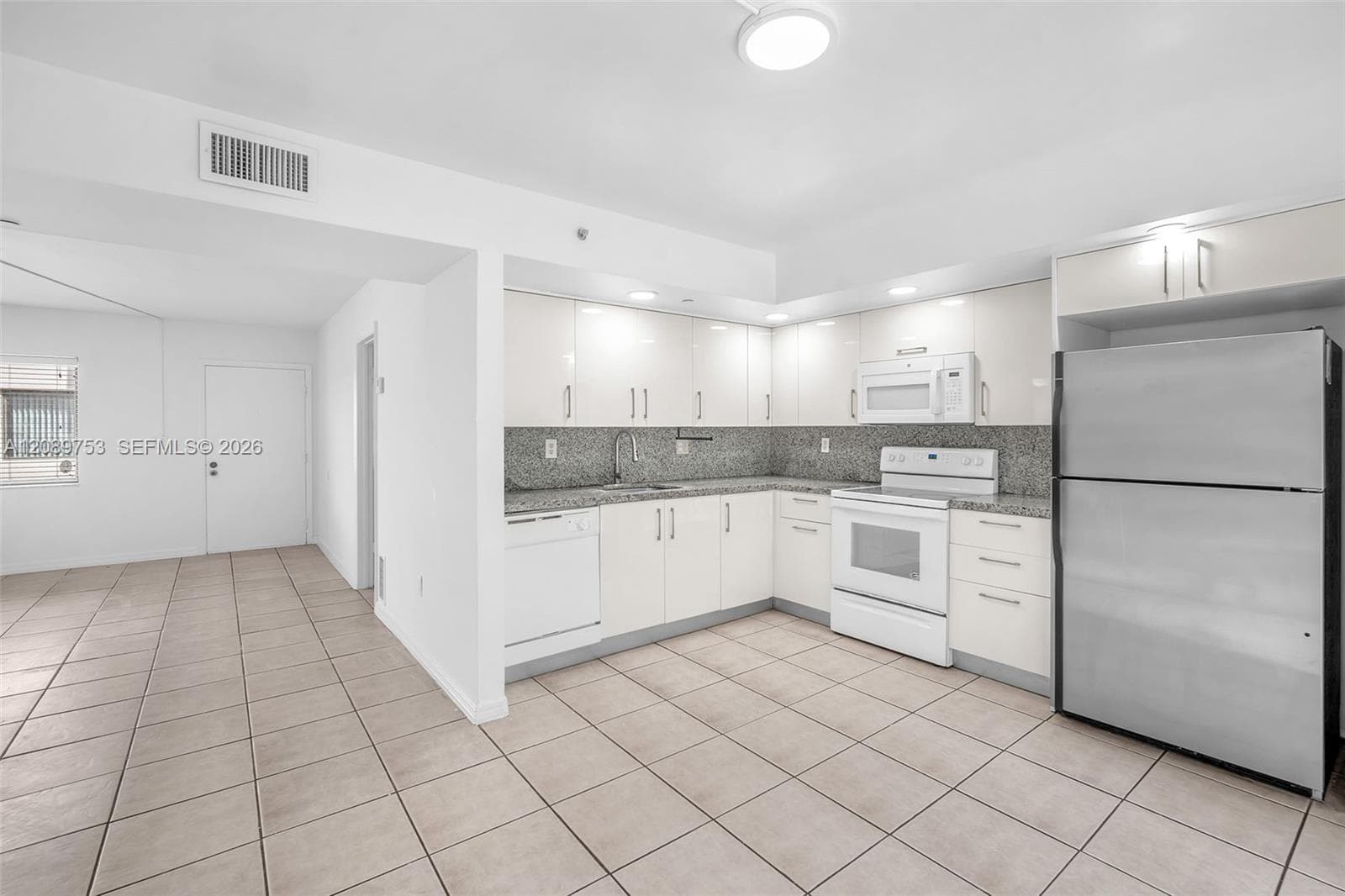 Kitchen featuring white cabinetry, stone-finish countertops, tile flooring, and integrated white appliances