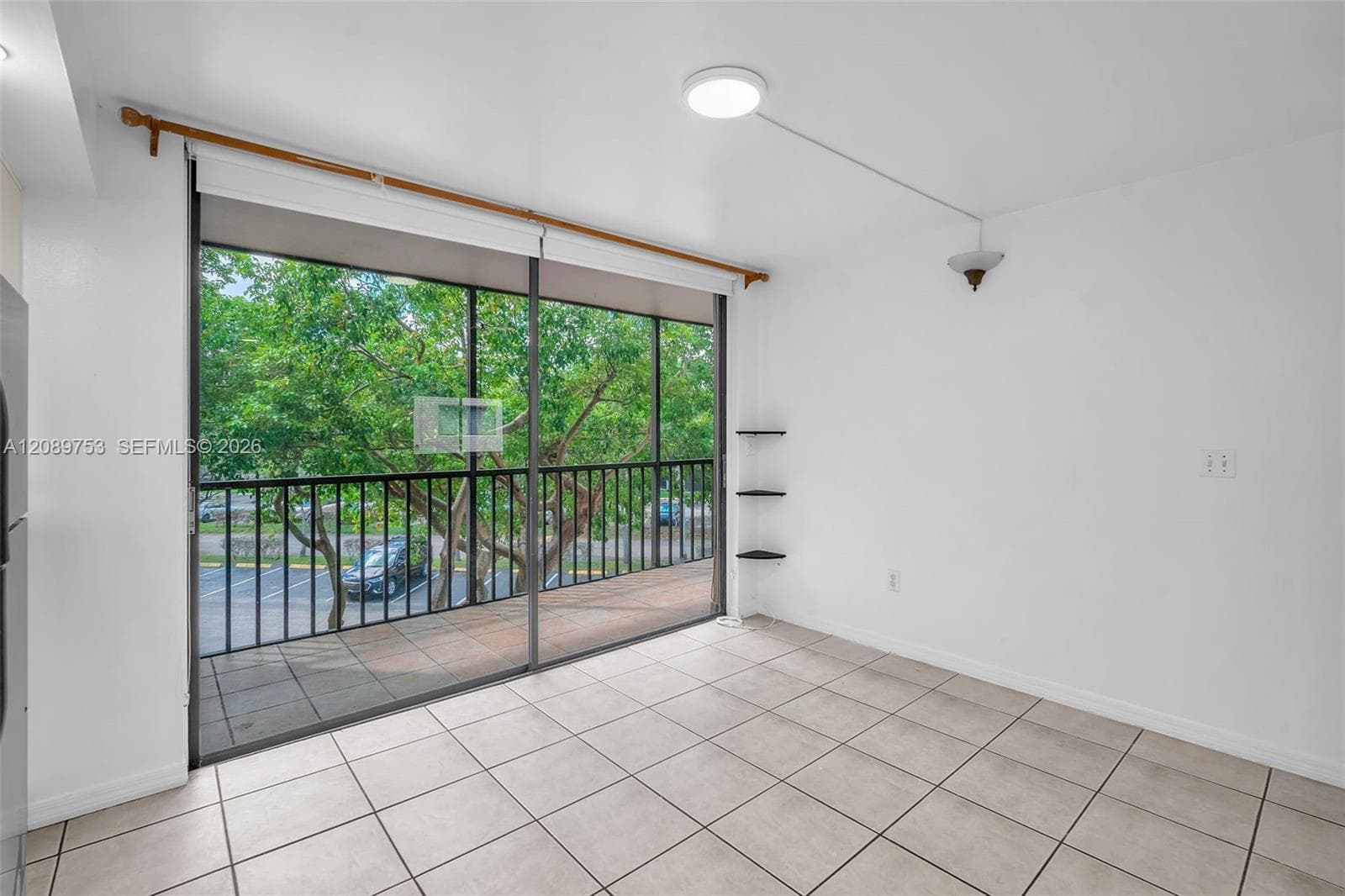 Large sliding glass door with access to a balcony, ceramic tile flooring, and wall-mounted shelving