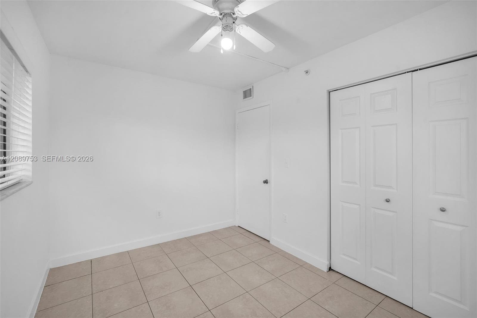 Room featuring ceramic tile flooring, a ceiling fan with light fixture, and double-panel closet doors