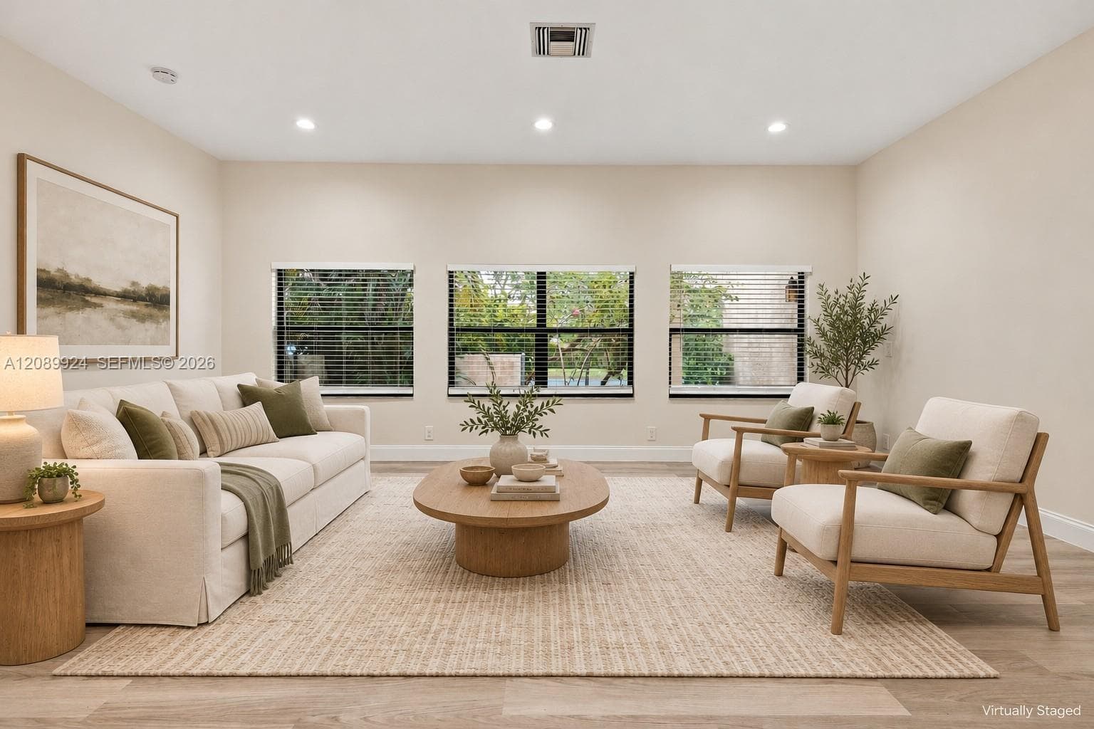 Living area featuring neutral wall tones, wood-finish flooring, and three oversized windows with horizontal blinds