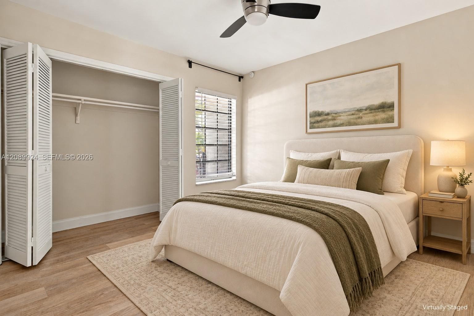 Wood-finish flooring, ceiling fan with integrated lighting, window with horizontal blinds, and a closet with bifold louvered doors