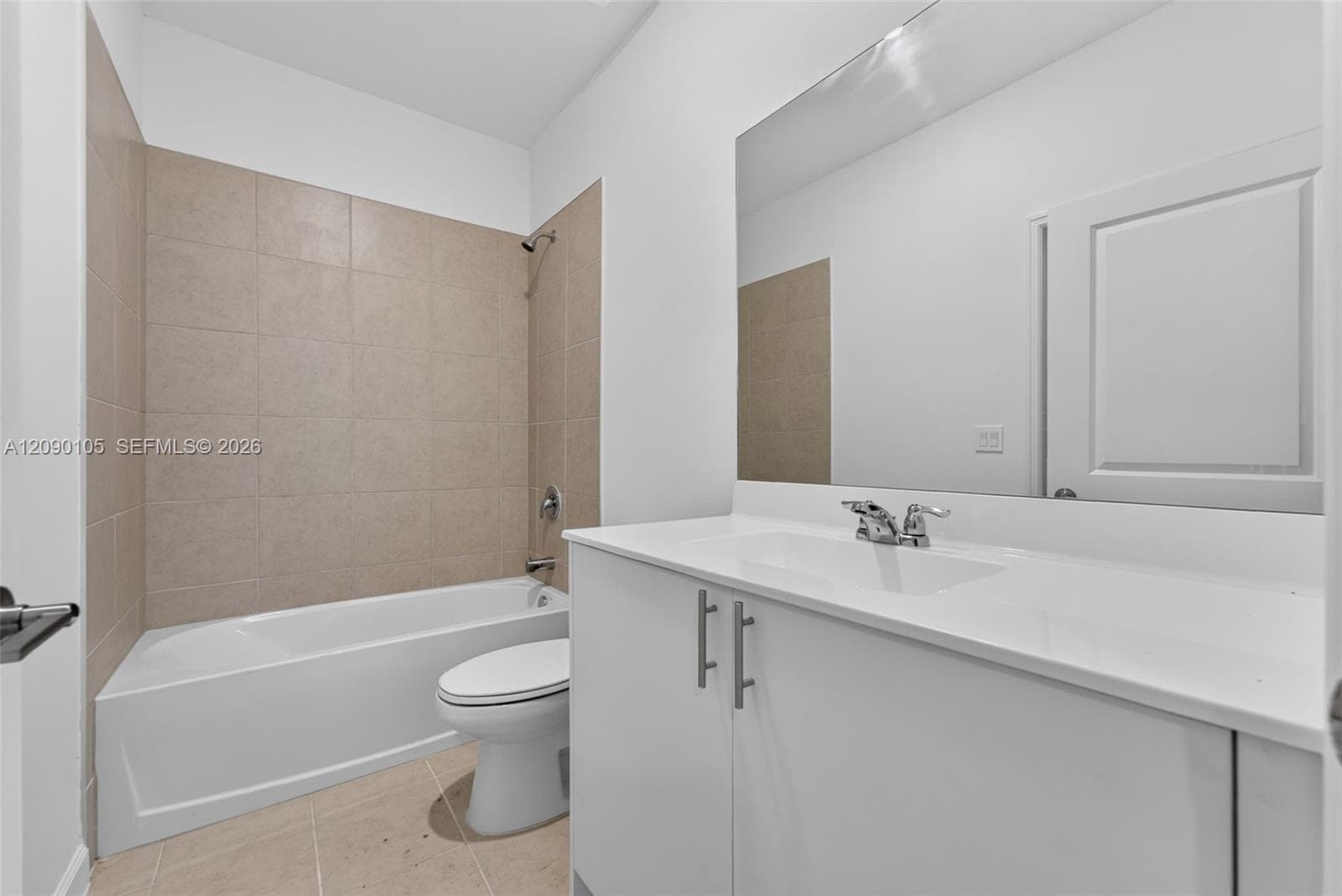 Bathroom featuring a white vanity cabinet, solid-surface countertop with an integrated sink, large wall-mounted mirror, and a tub-shower combination with ceramic tile surround