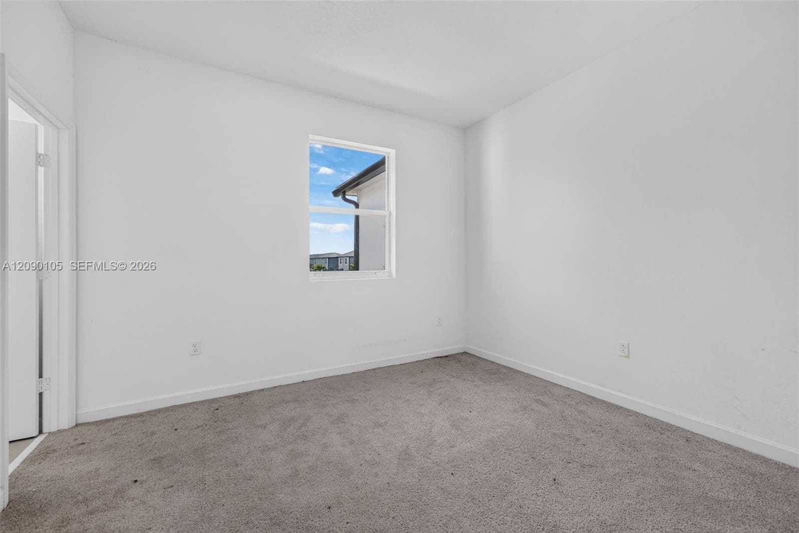 Neutral interior space featuring high-contrast walls, carpeting, and a single-pane window