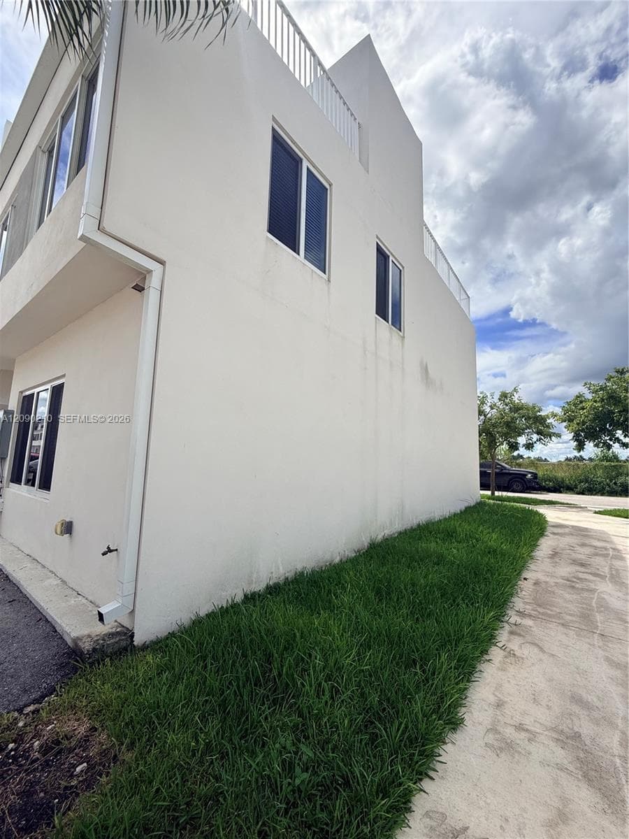 Stucco exterior featuring dual-level roof decks with white metal railings and rectangular windows