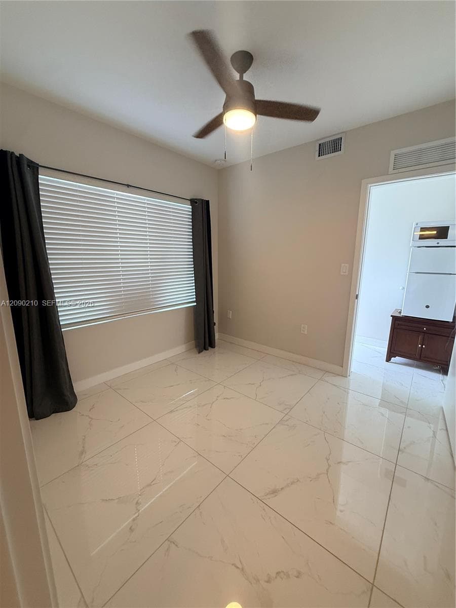 Large-format polished tile flooring, window with integrated blinds, and ceiling fan with integrated lighting