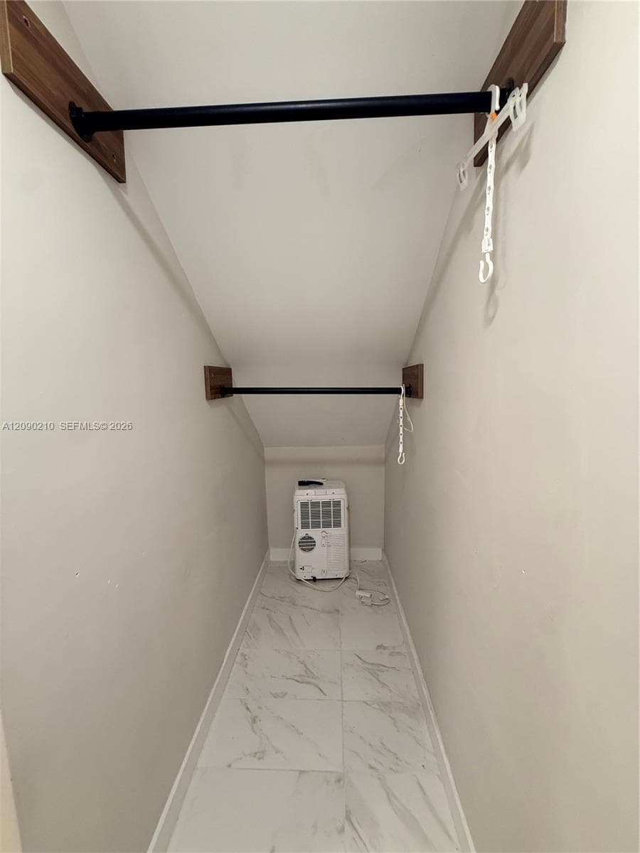 Storage area featuring tile flooring and dual black metal garment rods mounted on wood-finish supports