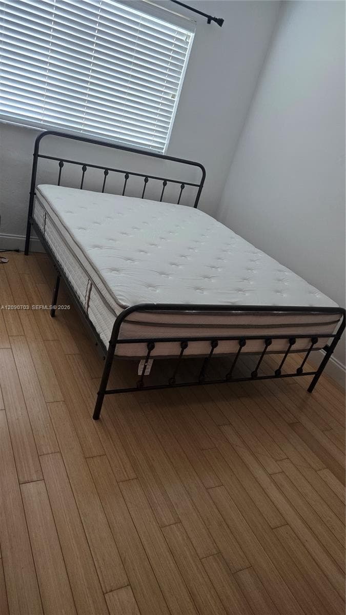 Room featuring wood-finish flooring and horizontal slat blinds