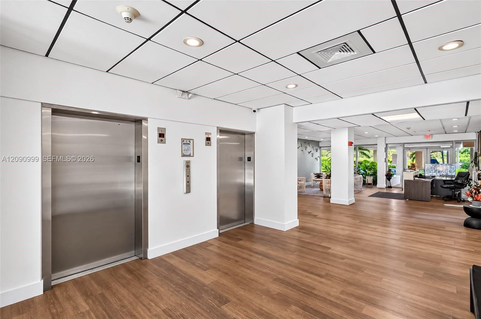 Lobby featuring dual stainless steel elevators, recessed lighting, drop ceiling, and wood-finish flooring