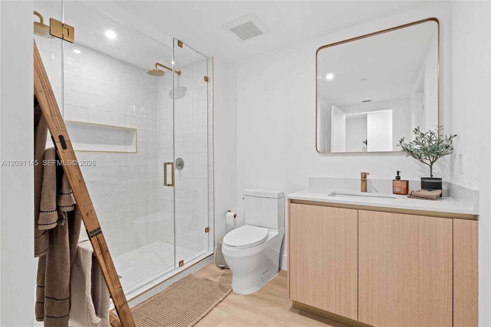 Glass-enclosed shower with a built-in niche, white subway tile surround, and gold-finish fixtures
