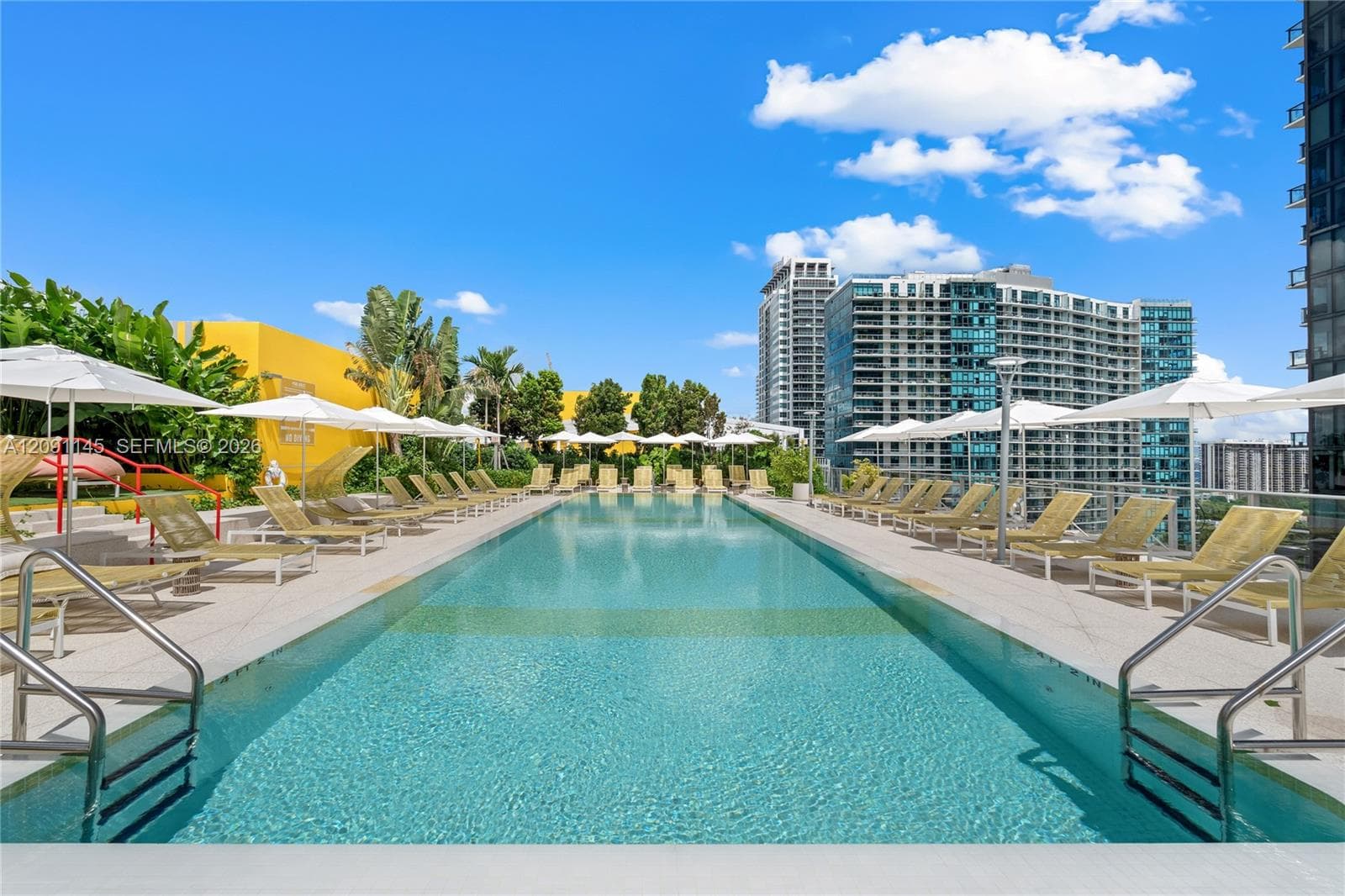 Expansive outdoor swimming pool with surrounding lounge chairs and umbrellas