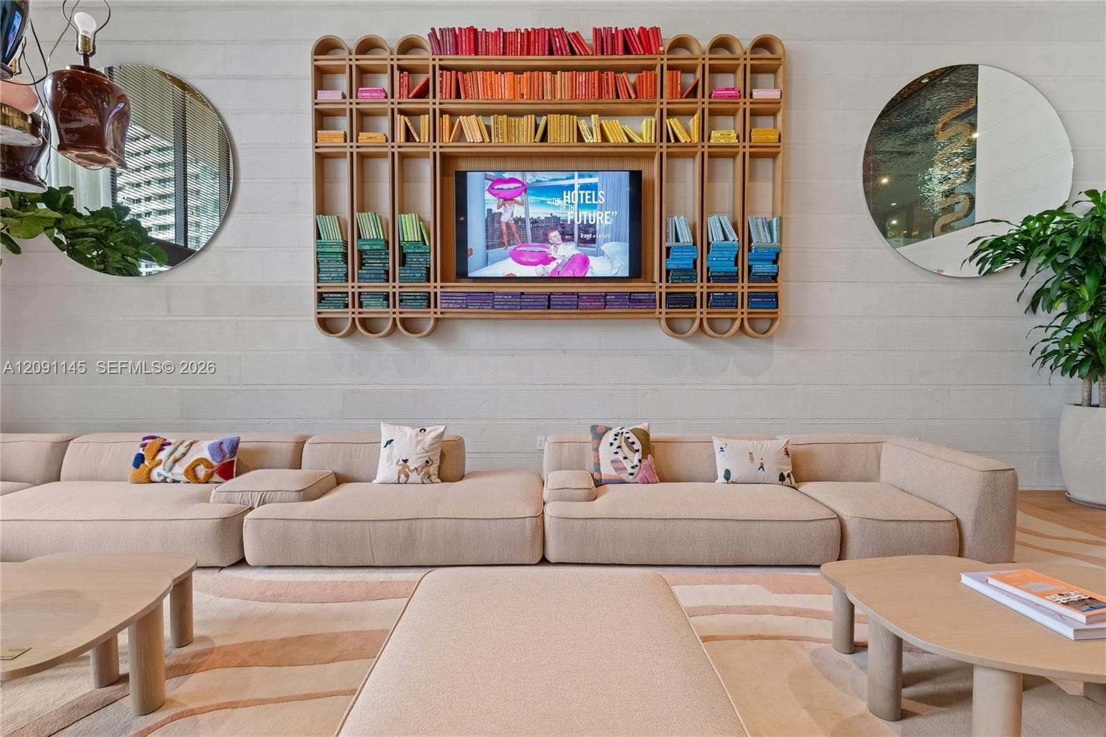 Built-in media console with integrated shelving, two round wall-mounted mirrors, and a neutral sectional sofa