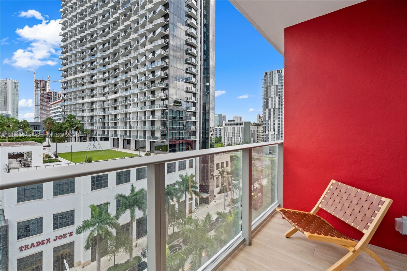 Balcony with glass railing, wood-finish flooring, and a vibrant red accent wall