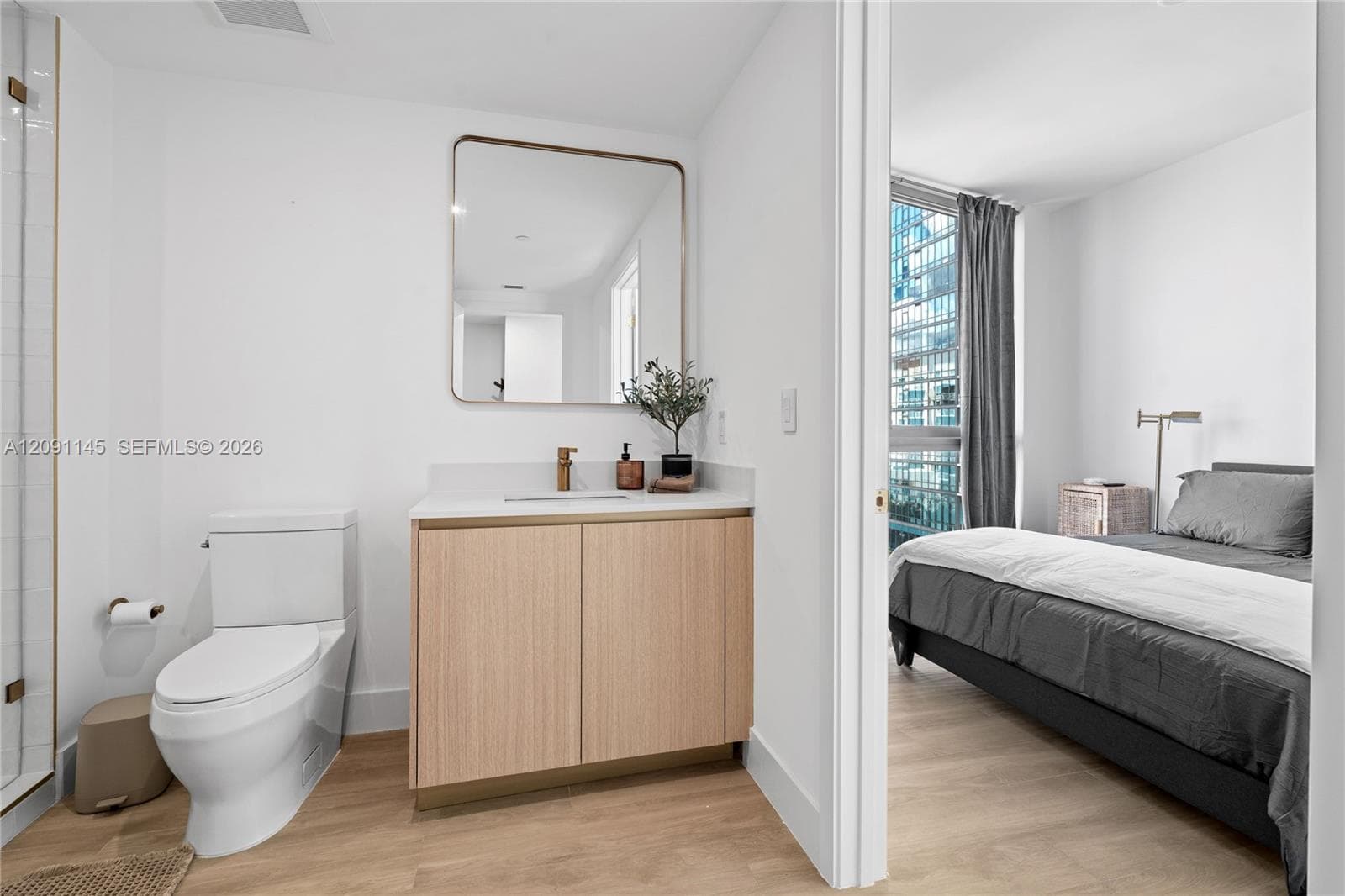 Bathroom featuring a light wood-finish vanity with a white countertop, rectangular framed mirror, and a modern toilet