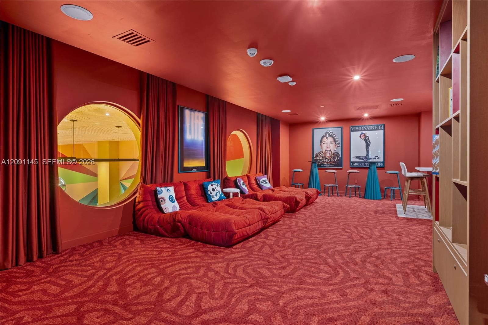 Recessed lighting, round windows, built-in shelving, full-height curtains, and patterned carpeting