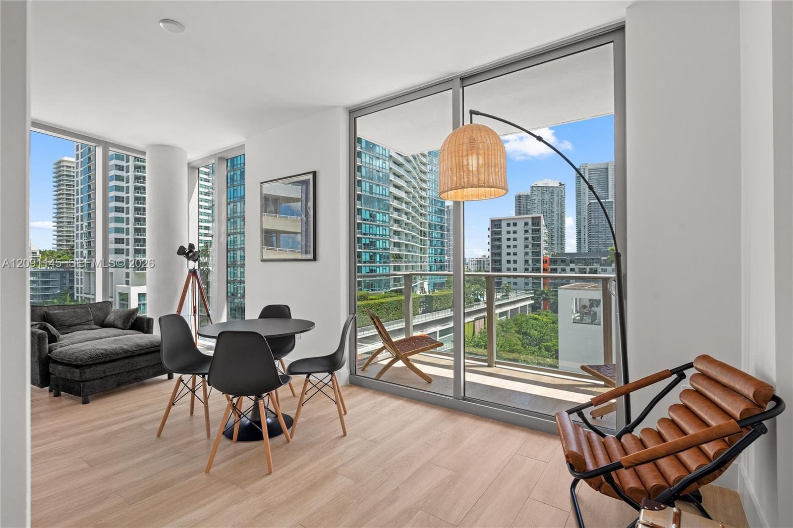 Floor-to-ceiling windows, wood-finish flooring, white walls, and a private balcony