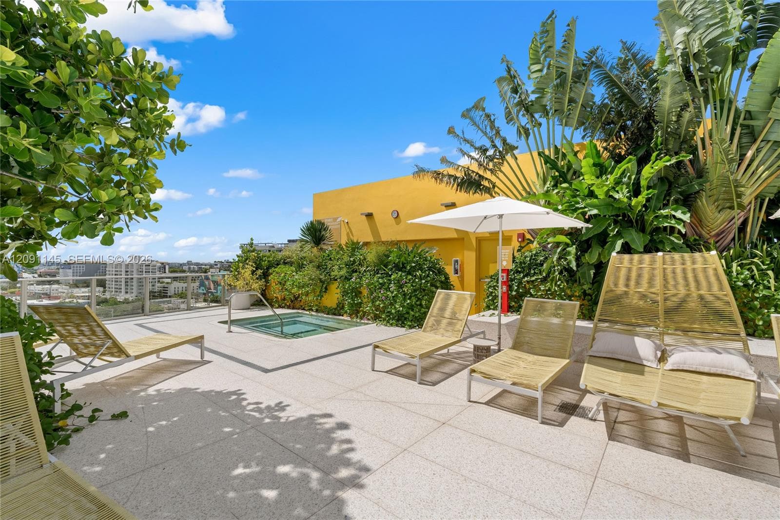 Rooftop terrace featuring a built-in spa, expansive paved surfacing, and lush tropical landscaping