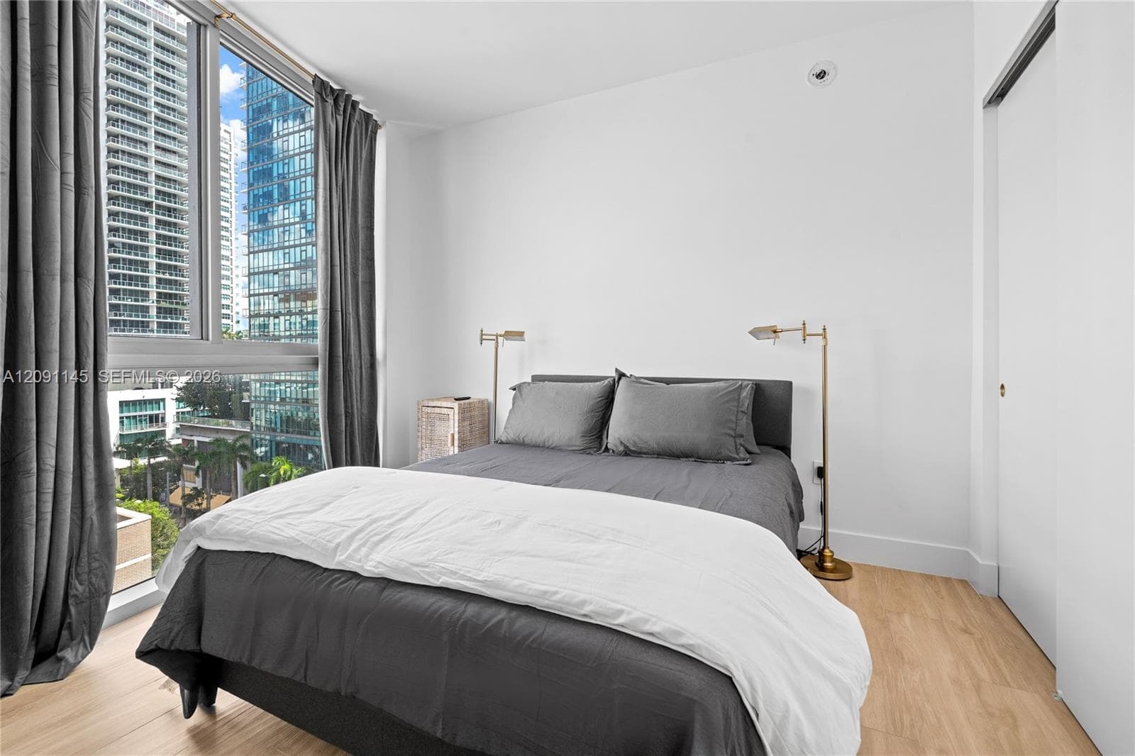 Expansive window with urban and green space scenery, wood-finish flooring, recessed lighting, and a sliding door closet