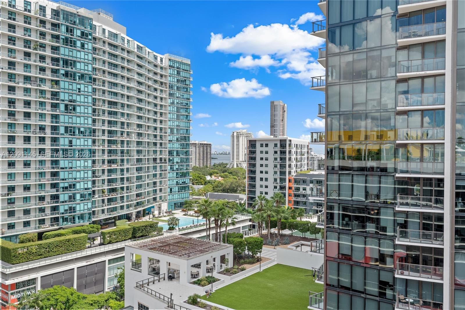 Cityscape featuring multiple high-rise buildings, an outdoor pool area, and manicured green spaces