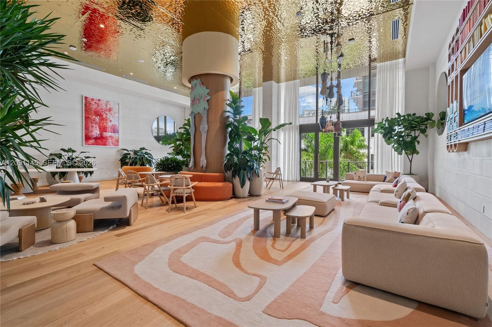 High ceilings with a reflective gold-toned finish, wood-finish flooring, floor-to-ceiling windows, and white wall finishes