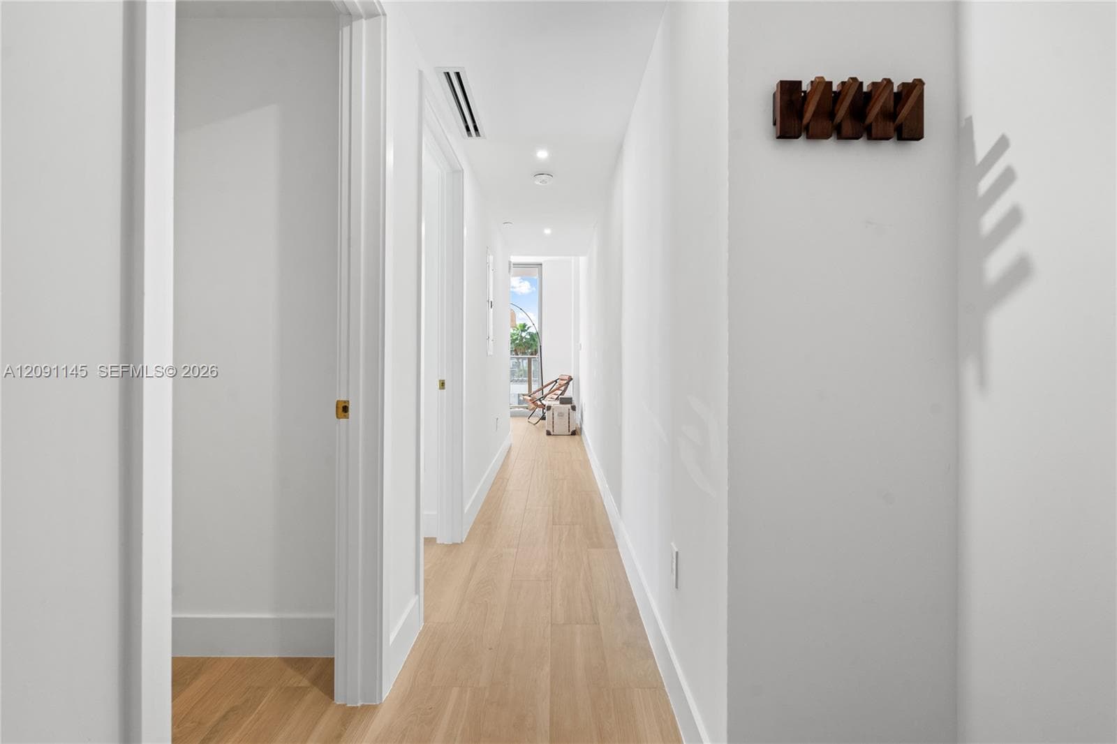 Recessed lighting, light wood-finish flooring, white walls, white trim, and a wood-finish wall-mounted coat rack