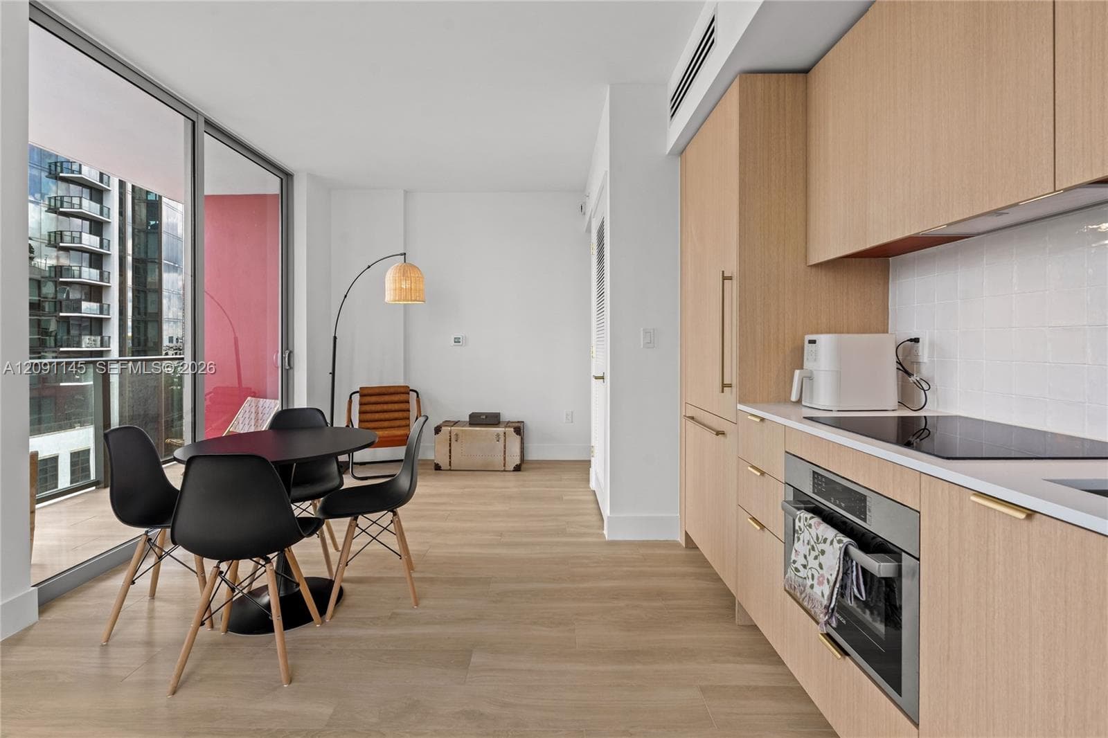 Kitchen with integrated appliances, light wood-finish cabinetry, and white tile backsplash