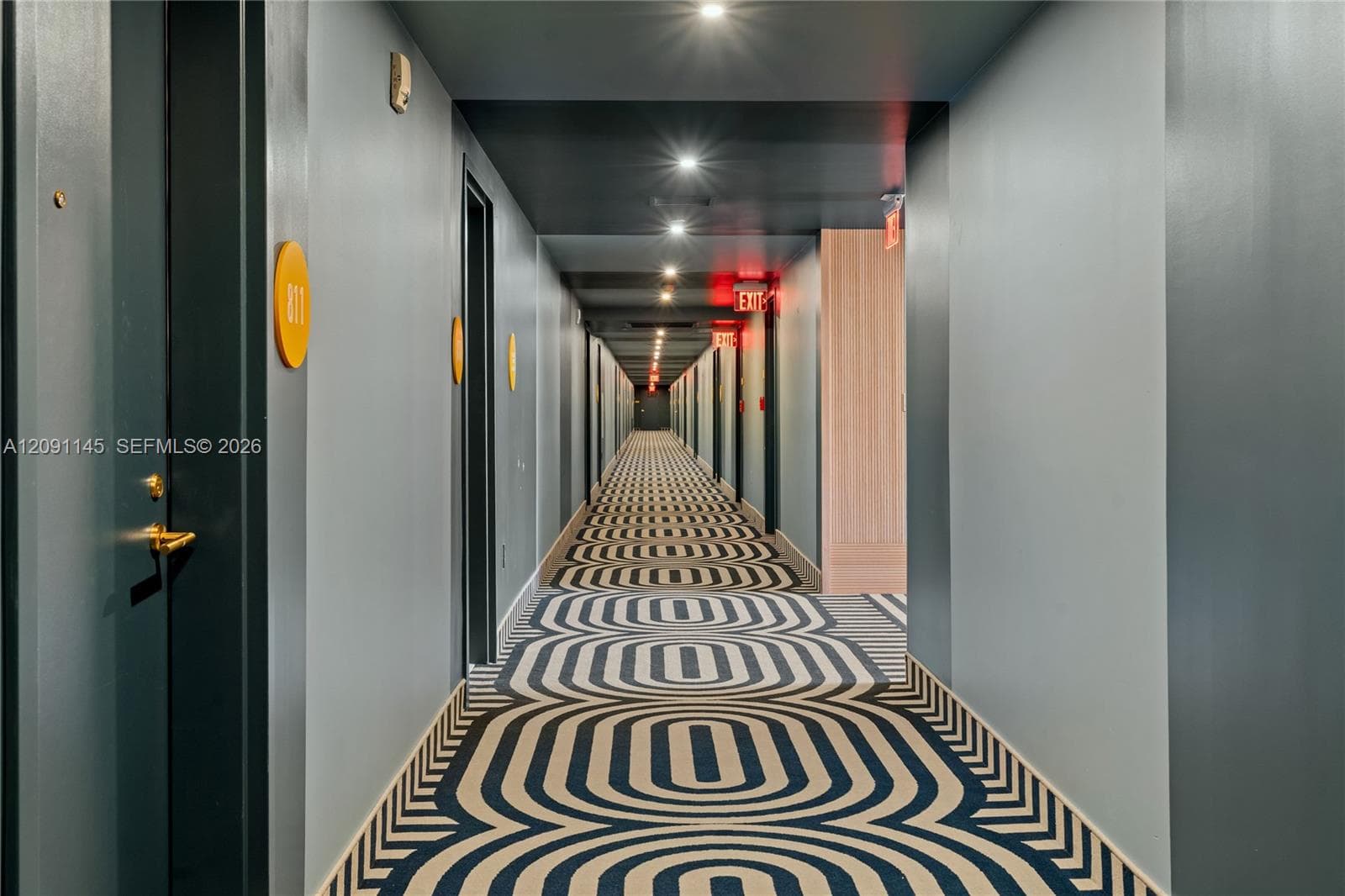 Hallway with patterned carpet, recessed lighting, and wall-mounted room indicators