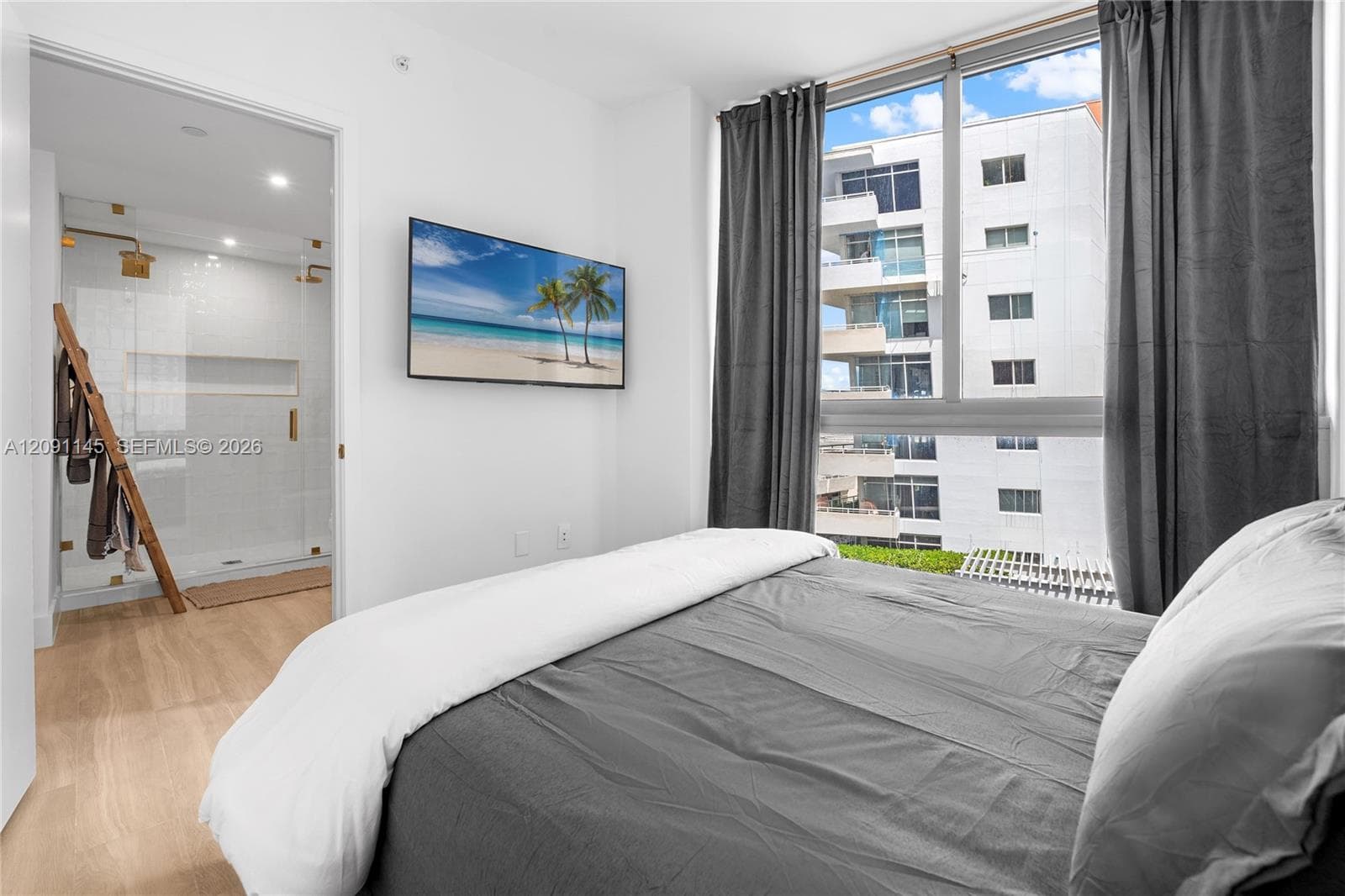 Wall-mounted television, wood-finish flooring, full-height window, glass-enclosed shower, built-in shower niche