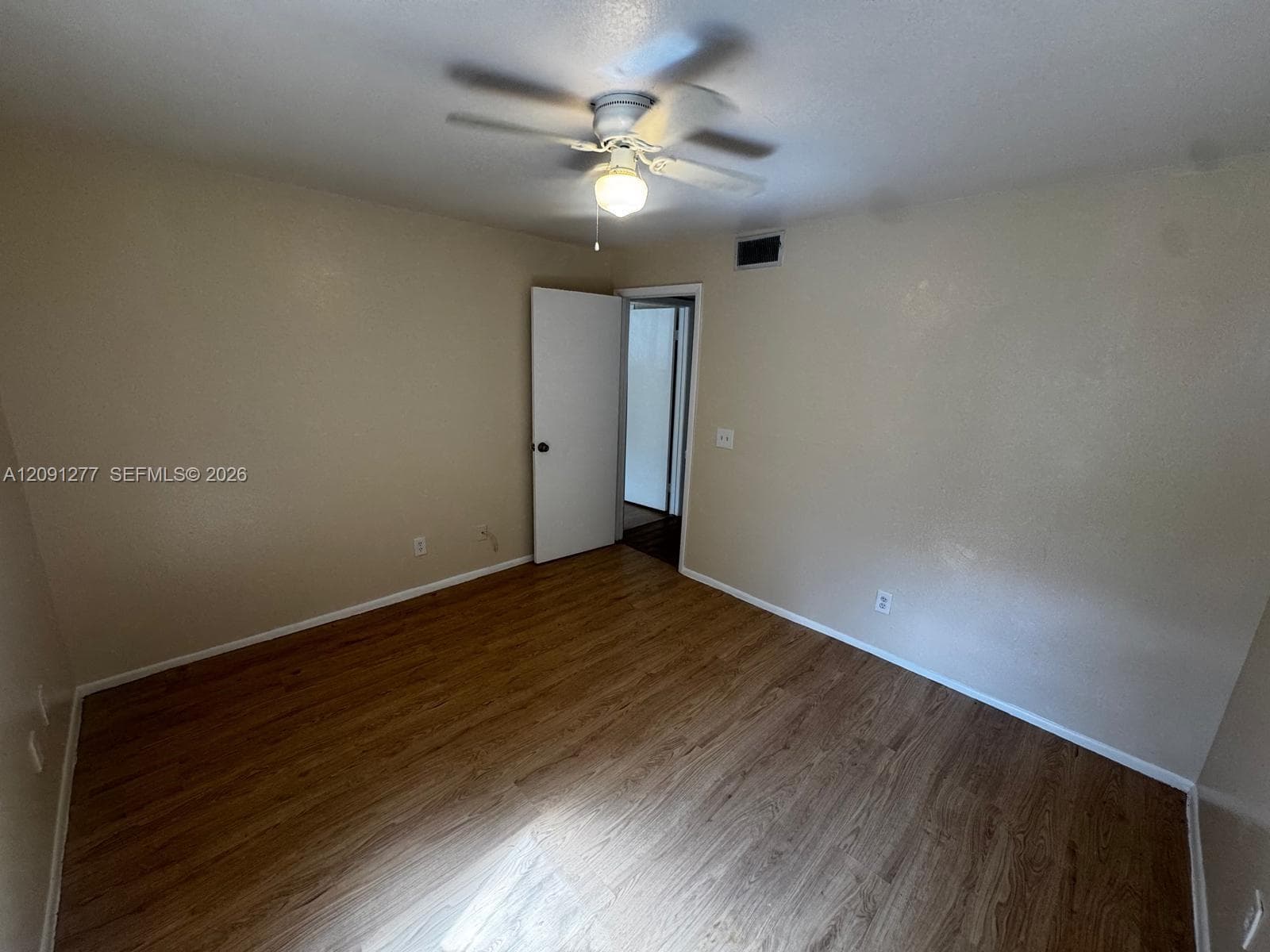 Room featuring wood-finish flooring, a ceiling fan with integrated lighting, and a neutral wall finish