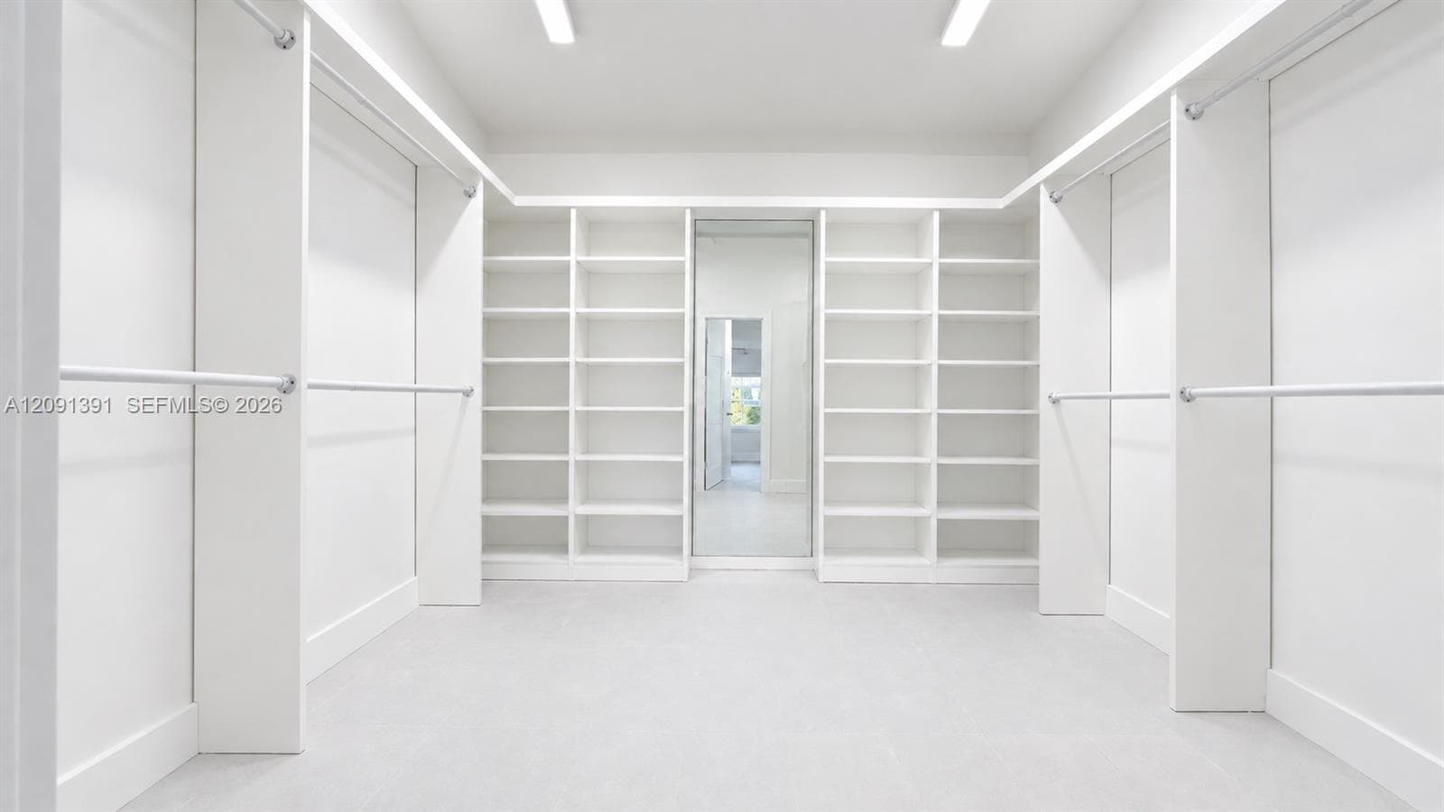 Walk-in closet featuring floor-to-ceiling built-in shelving, full-length mirror, and multi-level hanging rods