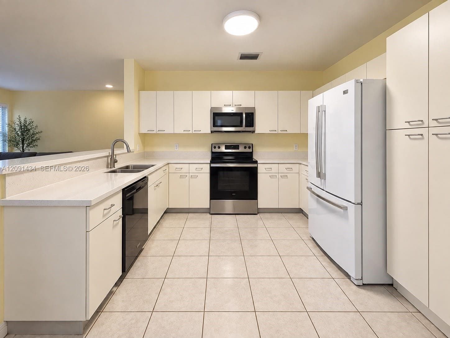 Kitchen featuring white cabinetry, stainless steel appliances, solid surface countertops, a dual-basin undermount sink, and tile flooring