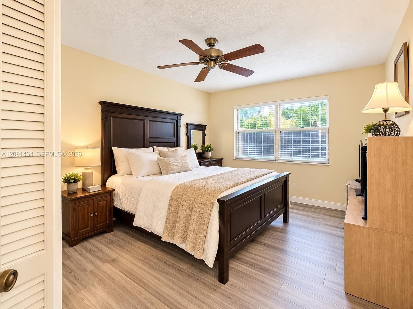 Room featuring wood-finish flooring, a multi-blade ceiling fan, and double-pane windows