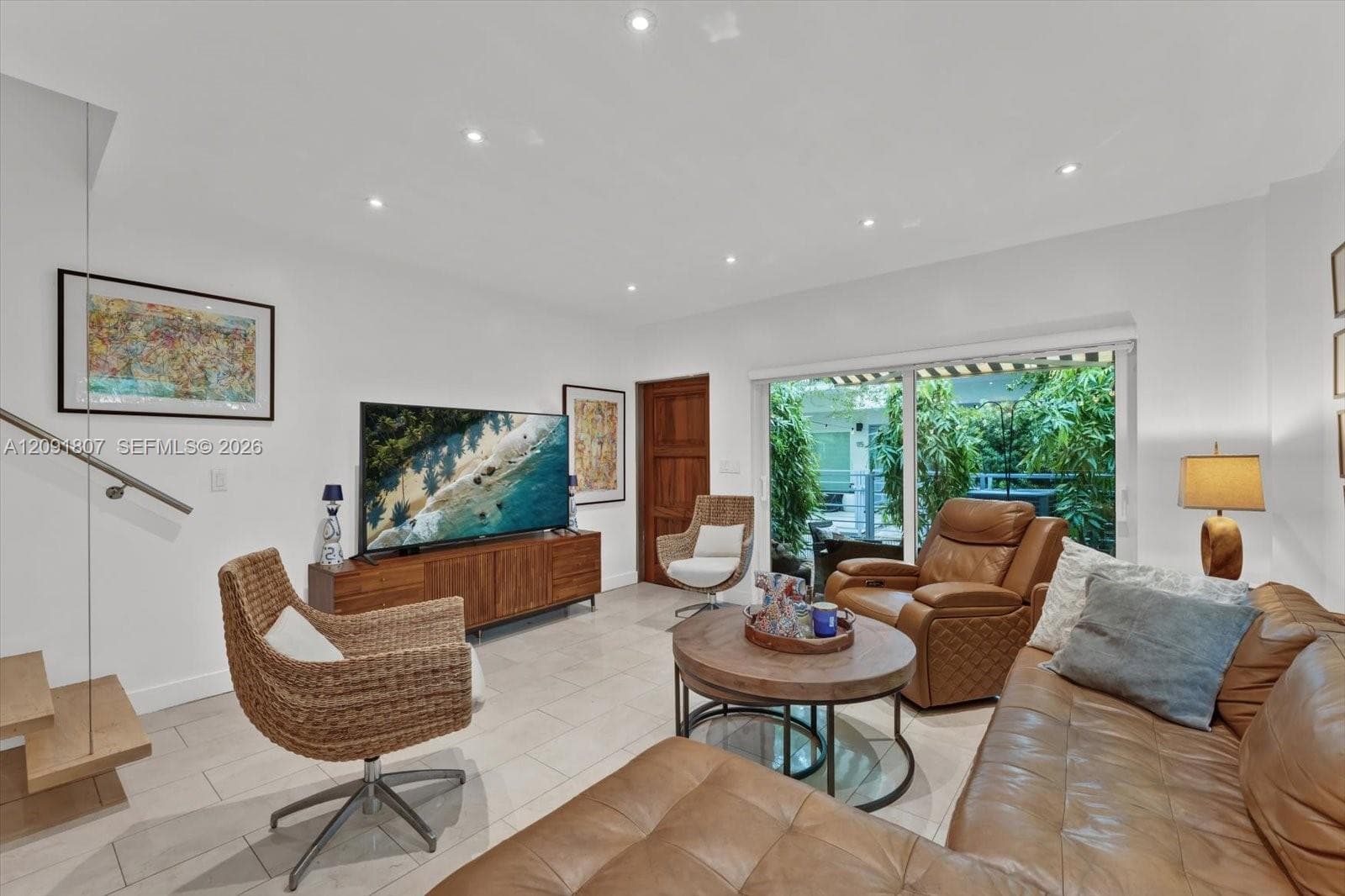 Large-format tile flooring, recessed ceiling lighting, sliding glass door with exterior access, and a floating wood-tread staircase with a glass panel railing