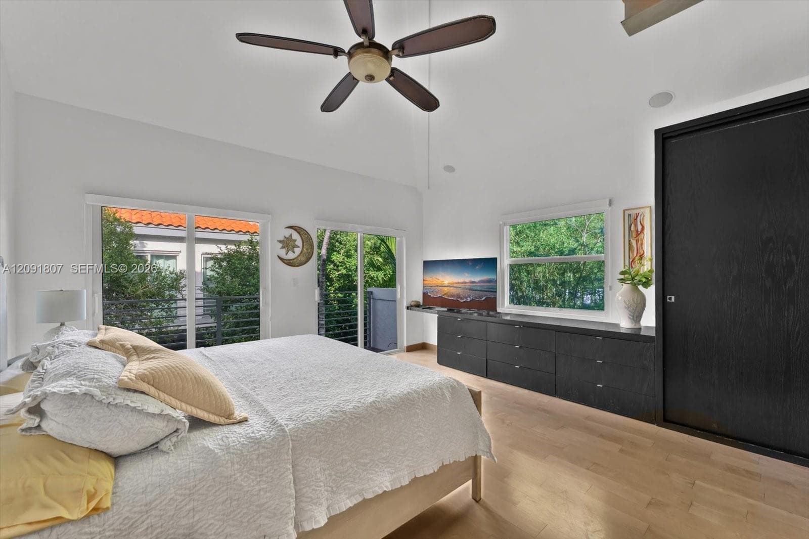 Vaulted ceilings, wood-finish flooring, built-in black cabinetry, ceiling fan, and sliding glass doors