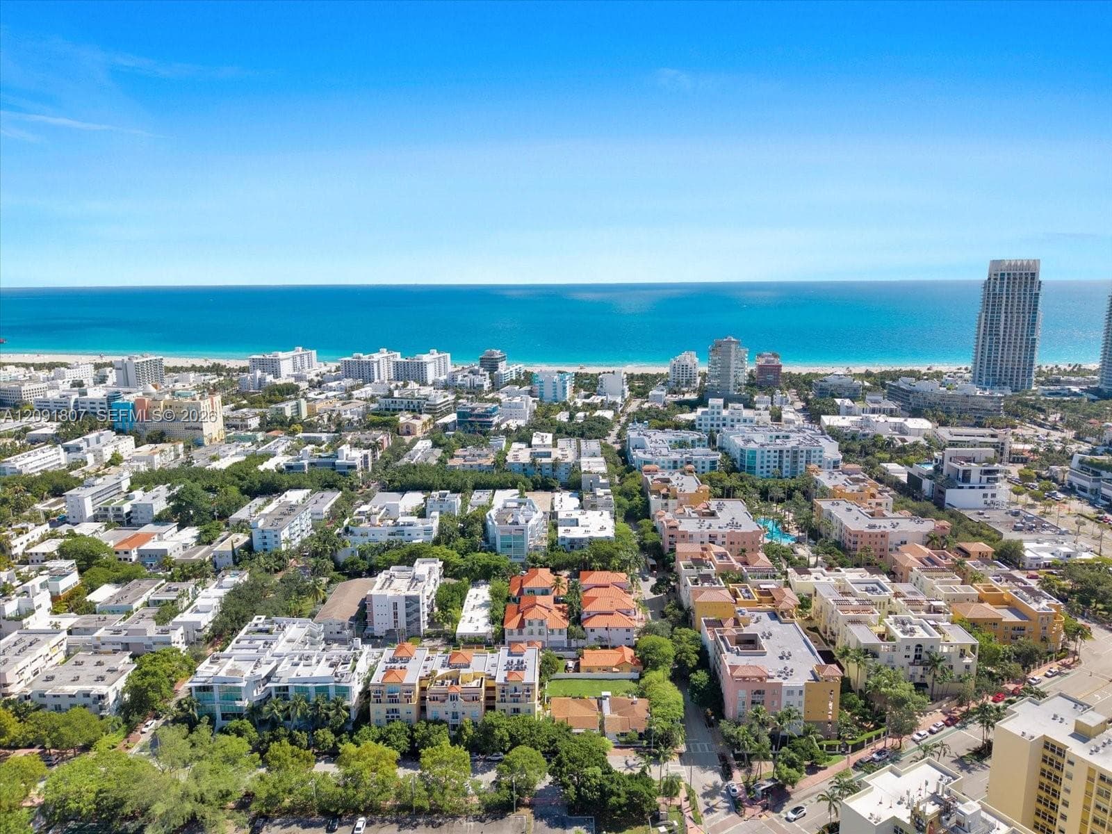 Aerial perspective featuring an expanse of mature tropical vegetation, proximity to coastal shoreline, and high-density urban development