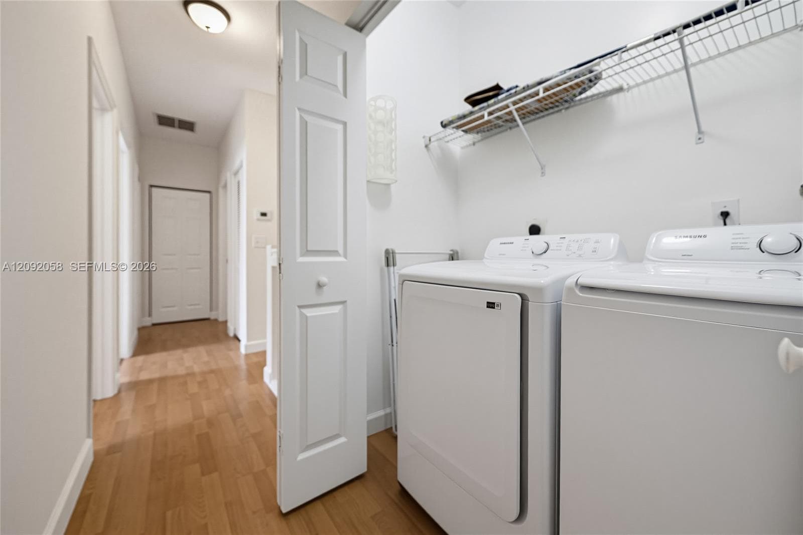 Laundry area featuring wood-finish flooring, a bi-fold door, and built-in wire shelving