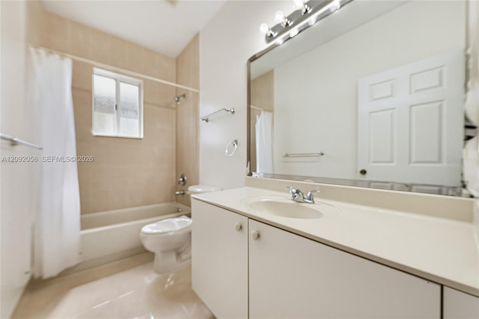 Bathroom featuring a vanity with integrated sink, large wall-mounted mirror, overhead vanity lighting, and a bathtub with tile surround
